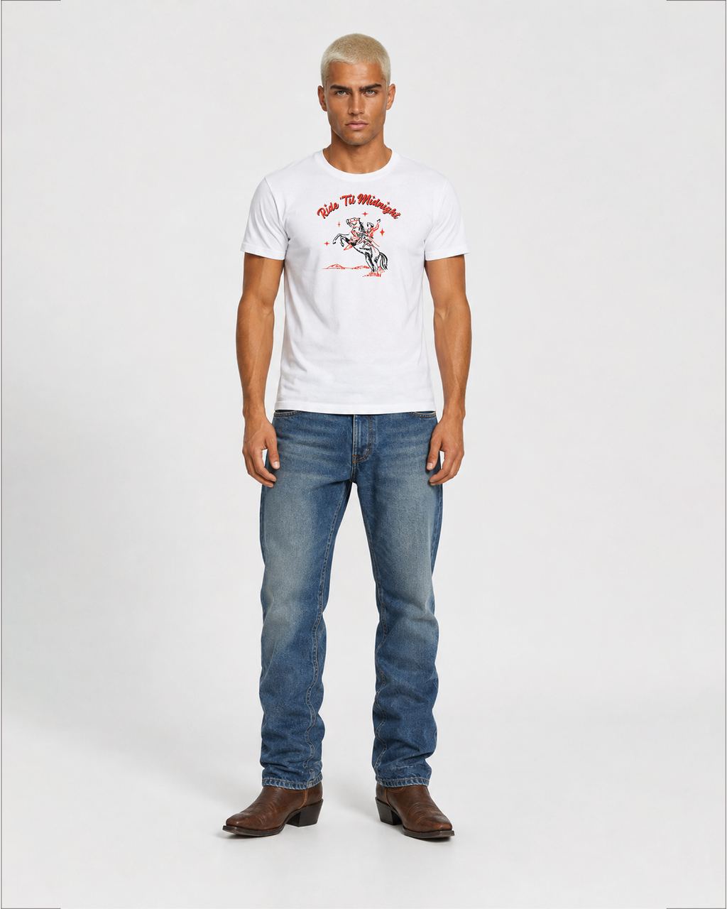 Male model wearing the white "Ride 'Til Midnight" western cowboy graphic t-shirt with jeans and boots, full-body standing shot